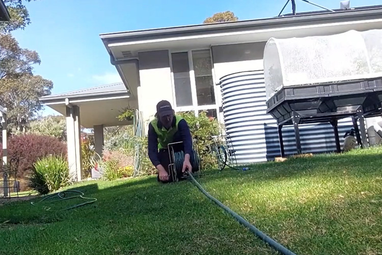 
Ending the workday, the narooma downpipe cleaner is tidying his equipment, including his hose.